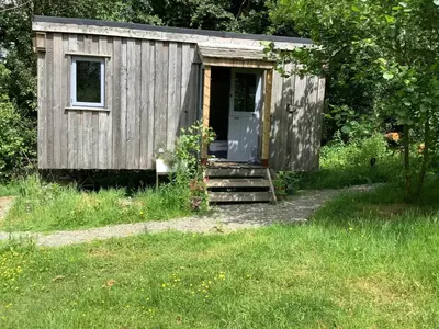 a wooden shed with a door in a field at The Charcoal Hut woodland retreat in Llandovery