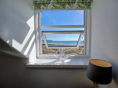 a window with a table and a chair in front of it at Seashell Apartment in Barmouth