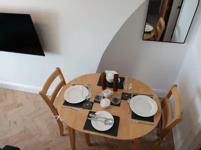 a wooden table with plates and glasses on it at Seashell Apartment in Barmouth