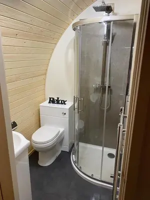 a bathroom with a toilet and a glass shower at Mynd View Pods Cedar in Craven Arms