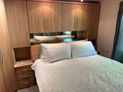 a bedroom with a bed and wooden cabinets at The Panorama View Luxury Retreat in Aberystwyth in Aberystwyth