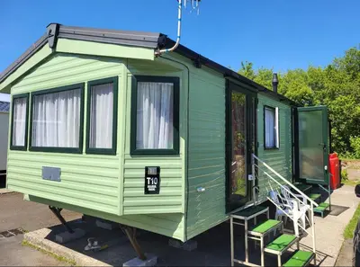 a green tiny house parked in a lot at River View Modern 3 Bedroom Pet Friendly in Clarach Bay in Aberystwyth