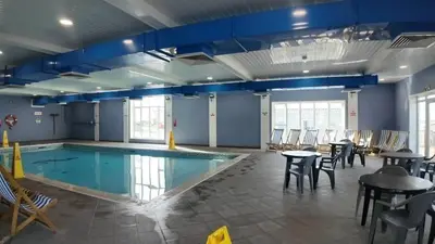 a swimming pool with tables and chairs around it at Awel Mor Beautiful Pet Friendly Chalet in Clarach Bay in Aberystwyth