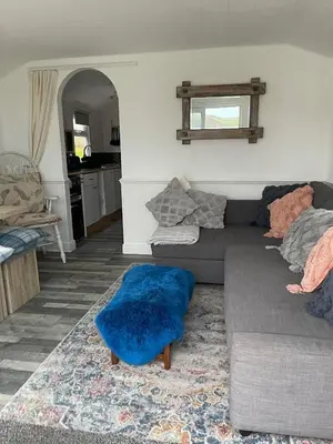 a living room with a couch and a blue pillow at Awel Mor Beautiful Pet Friendly Chalet in Clarach Bay in Aberystwyth