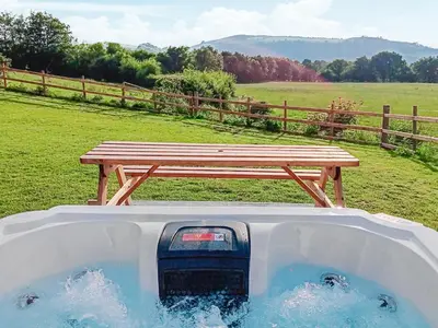 a hot tub with a picnic table and a bench at Teifi Cottage - Uk49590 in Llansawel
