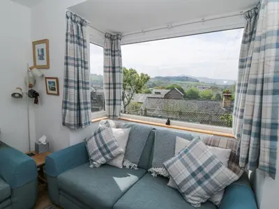 a living room with a blue couch and a large window at Brycheiniog View in Brecon