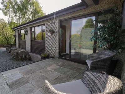 a patio with two chairs and a sliding glass door at Gilfach Bach in Dolgellau