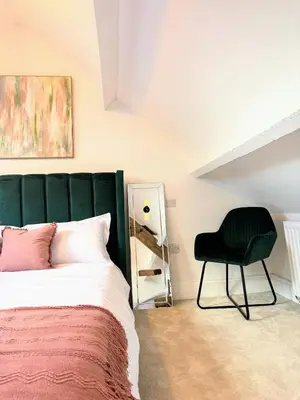 a bedroom with a green headboard and a black chair at Charming Stone Cottage Getaway in Dolgellau