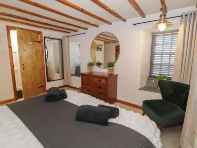 a bedroom with a bed and a chair and a mirror at Penygrisiau in Barmouth