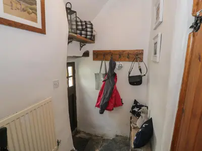 a hallway with a stairway with clothes hanging on the wall at Penygrisiau in Barmouth