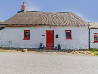 a white house with red windows and a red door at 2 Bed in Llanon oc-96072 in Pennant