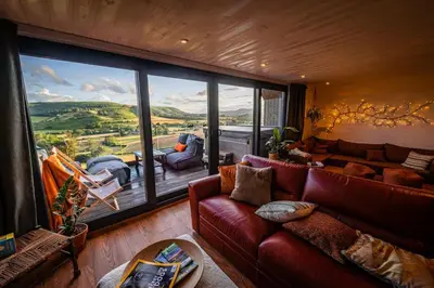 a living room with a couch and a large window at Oolert Treehouse in Hundred House