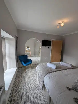 a hotel room with two beds and a blue chair at Bwthyn Y Mor in Llanddwywe