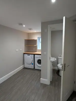 a bathroom with a toilet and a sink and a washing machine at Bwthyn Y Mor in Llanddwywe