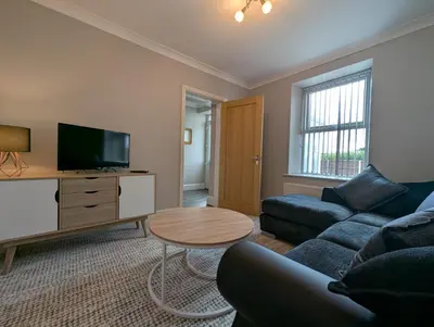 a living room with a couch and a tv and a table at Bwthyn Y Mor in Llanddwywe