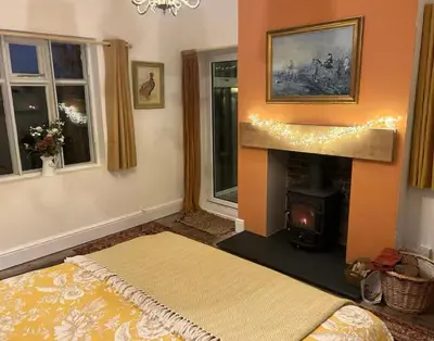 a living room with a fireplace and a bed and windows at Oaklands Farm in Preesgreen