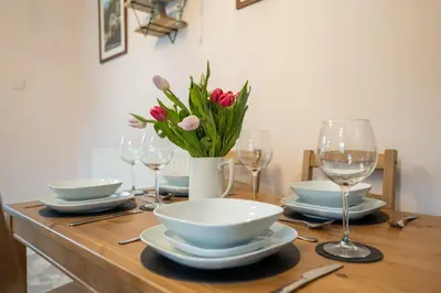 a table with plates and glasses and a vase of flowers at Cosy townhouse with log burner in Dolgellau