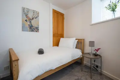 a bedroom with a white bed and a table at Cosy townhouse with log burner in Dolgellau