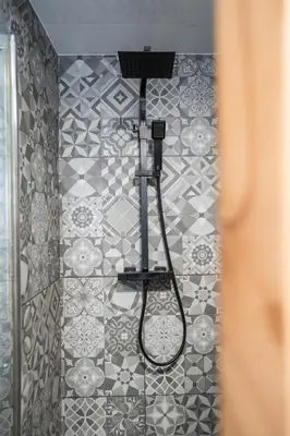 a shower with a shower head on a tiled wall at Cosy townhouse with log burner in Dolgellau