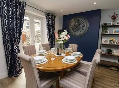 a dining room with a table and a clock on the wall at Beautiful cottage with log burner in Dolgellau
