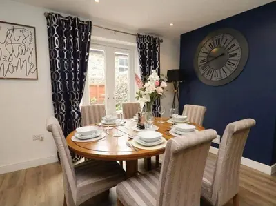 a dining room table with chairs and a clock on the wall at Beautiful cottage with log burner in Dolgellau