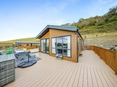 a wooden deck with a small cabin on the beach at Hillfort Lodge in Llanrhystyd