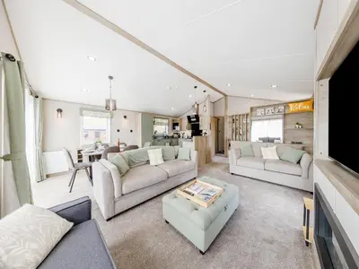 a living room with two couches and a tv at Hillfort Lodge in Llanrhystyd