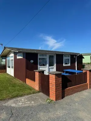 a small house with a fence in front of it at Y Caban Caru in Tywyn