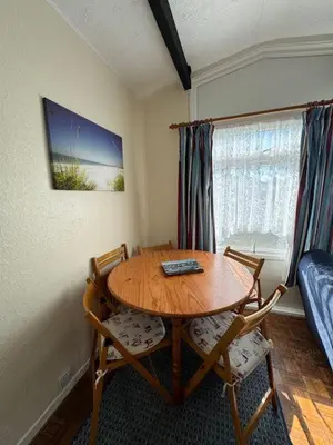 a room with a table and two chairs and a bed at Y Caban Caru in Tywyn