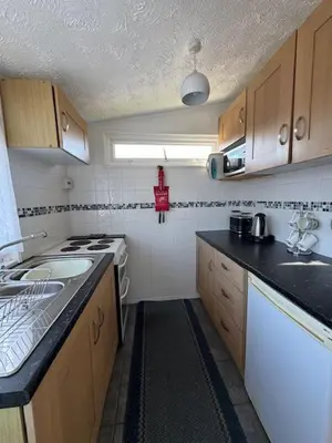 a small kitchen with a stove and a sink at Y Caban Caru in Tywyn