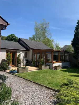 a house with glass doors and a yard at Cysgod Bach & Caban y Saer Cottages in Bala