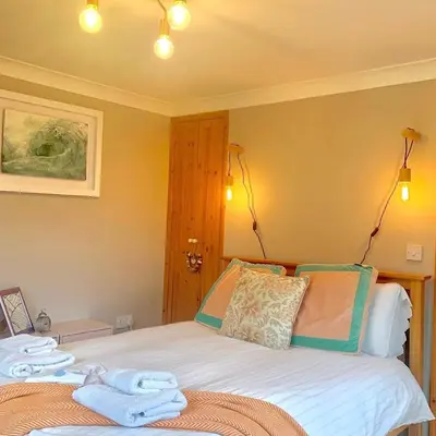 a bedroom with a bed with towels on it at Cysgod Bach & Caban y Saer Cottages in Bala