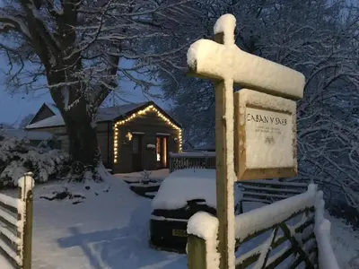 a cabin in the snow with lights on it at Cysgod Bach & Caban y Saer Cottages in Bala