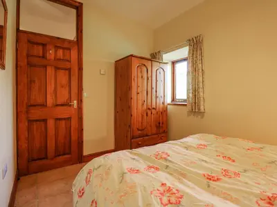 a bedroom with a bed and a wooden cabinet at Cae'n Y Coed Barn in Talsarnau