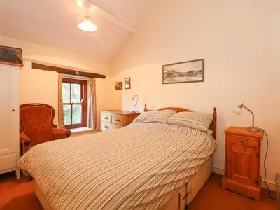 a bedroom with a bed and a dresser and a window at Cae'n Y Coed Cottage in Talsarnau