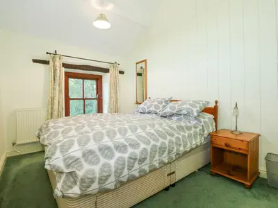 a bedroom with a bed and a nightstand and a window at Cae'n Y Coed Cottage in Talsarnau
