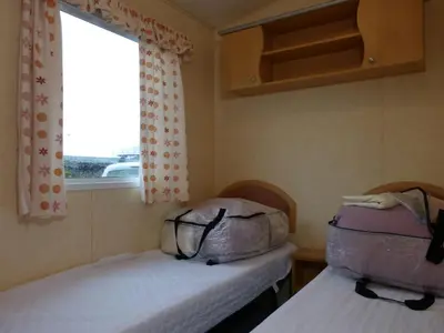two beds in a small room with a window at Northfield Holiday Park in Borth