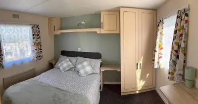 a small bedroom with a bed and a desk at Northfield Holiday Park in Borth