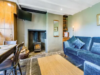 a living room with a blue couch and a fireplace at 3 Legged Duck Cottage in Yspytty-Ystwyth