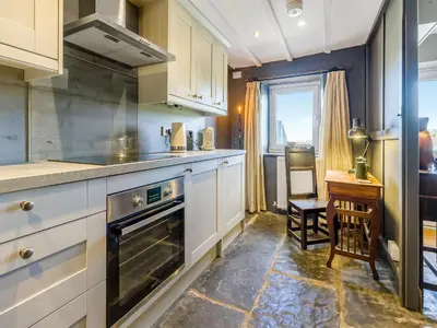 a kitchen with white cabinets and a table and a window at 3 Legged Duck Cottage in Yspytty-Ystwyth