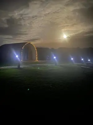 a lit up arch in front of a building at night at Mynd View Pods Ash in Craven Arms