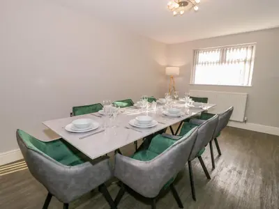 a dining room with a table and green chairs at Bwthyn Y Mor in Llanddwywe