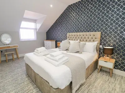 a bedroom with a large bed with two towels on it at Bwthyn Y Mor in Llanddwywe