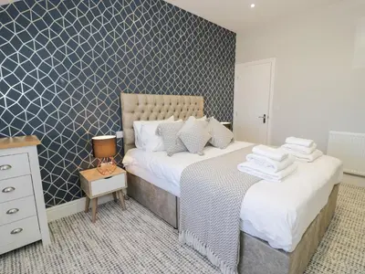 a bedroom with two beds and a blue and white wall at Bwthyn Y Mor in Llanddwywe