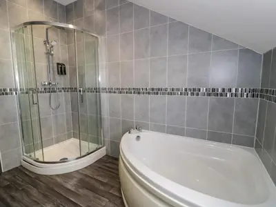 a bathroom with a shower and a tub and a toilet at Bwthyn Y Mor in Llanddwywe