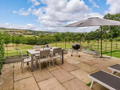 a patio with a table and an umbrella and a grill at 1 Bed in Hereford oc-42897 in Craswall