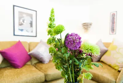 a vase filled with purple flowers in front of a couch at Maes Bach Boutique GUEST HOUSE TOWN CENTRE in Aberystwyth