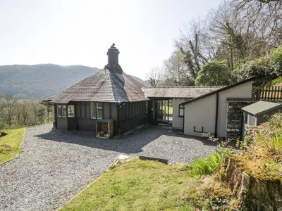 a house with a gravel driveway in front of it at Bwthyn y Coediwr The Woodcutters Cottage in Blaenau-Ffestiniog