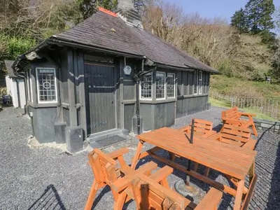 a wooden table and chairs in front of a building at Bwthyn y Coediwr The Woodcutters Cottage in Blaenau-Ffestiniog