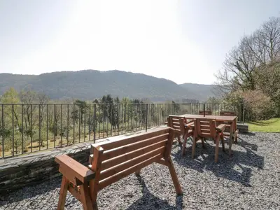 two wooden benches and a table in front of a fence at Bwthyn y Coediwr The Woodcutters Cottage in Blaenau-Ffestiniog